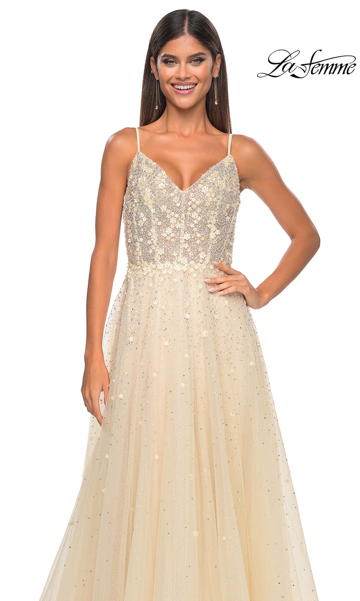 A woman in the La Femme Embellished Long A-Line Prom Dress 32215, a sleeveless light gold sequin gown with spaghetti straps, smiles and poses with one hand on her hip. The La Femme logo is visible in the top right corner.